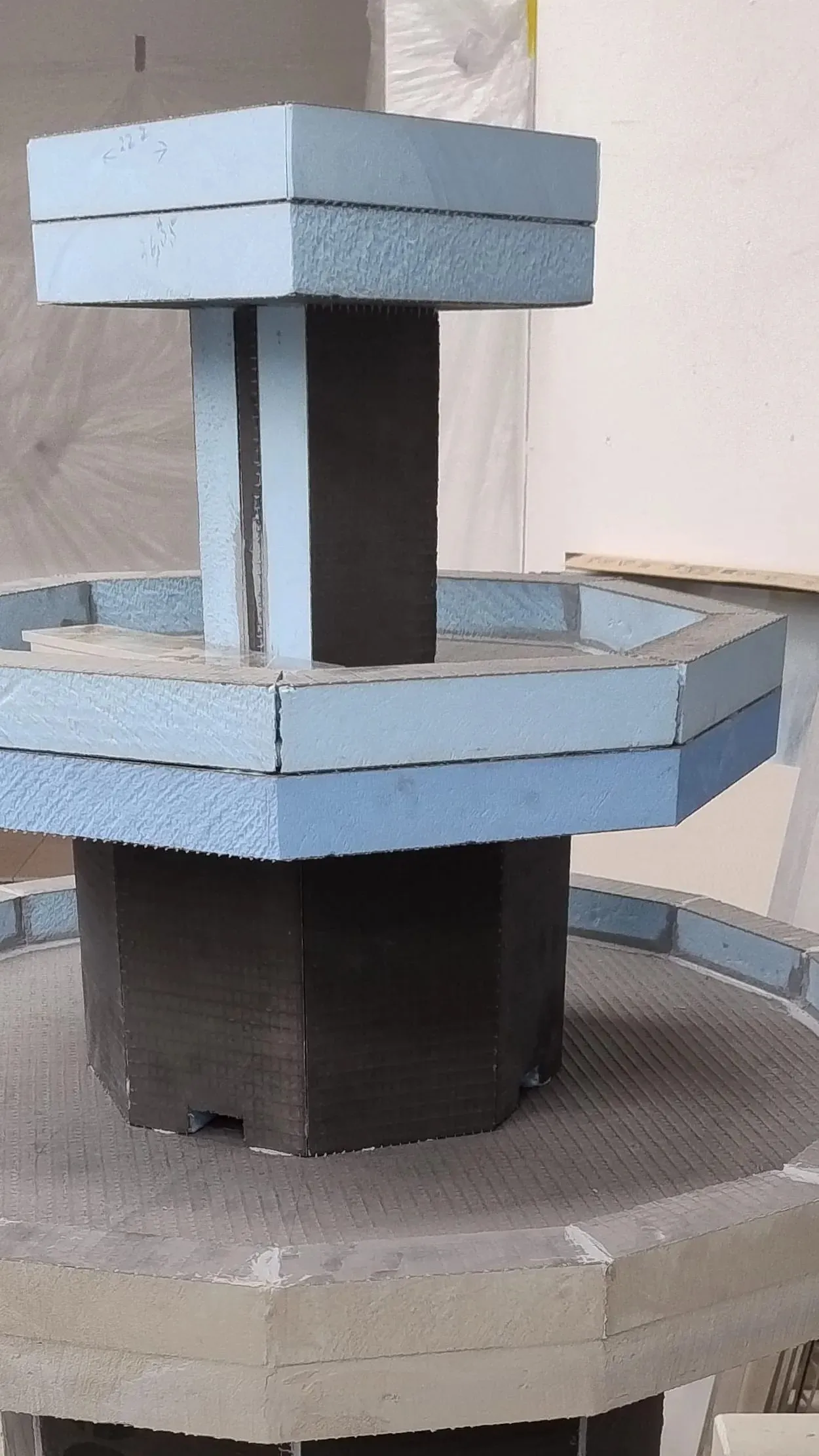 Unverkleideter Rohbau des Brunnens: achteckiger Korpus und Schale aus Bauplatten