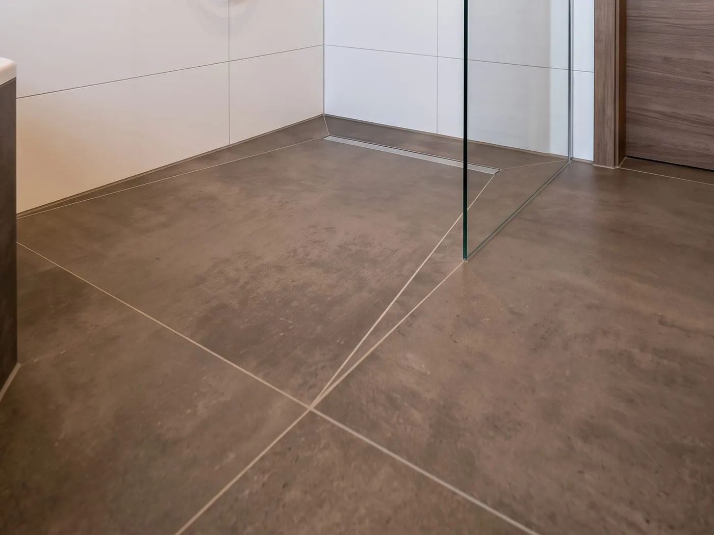 Bodengleiche Dusche mit wandbündiger Duschrinne, Gefälleschnitten im großformatigen Boden und Glasabtrennung