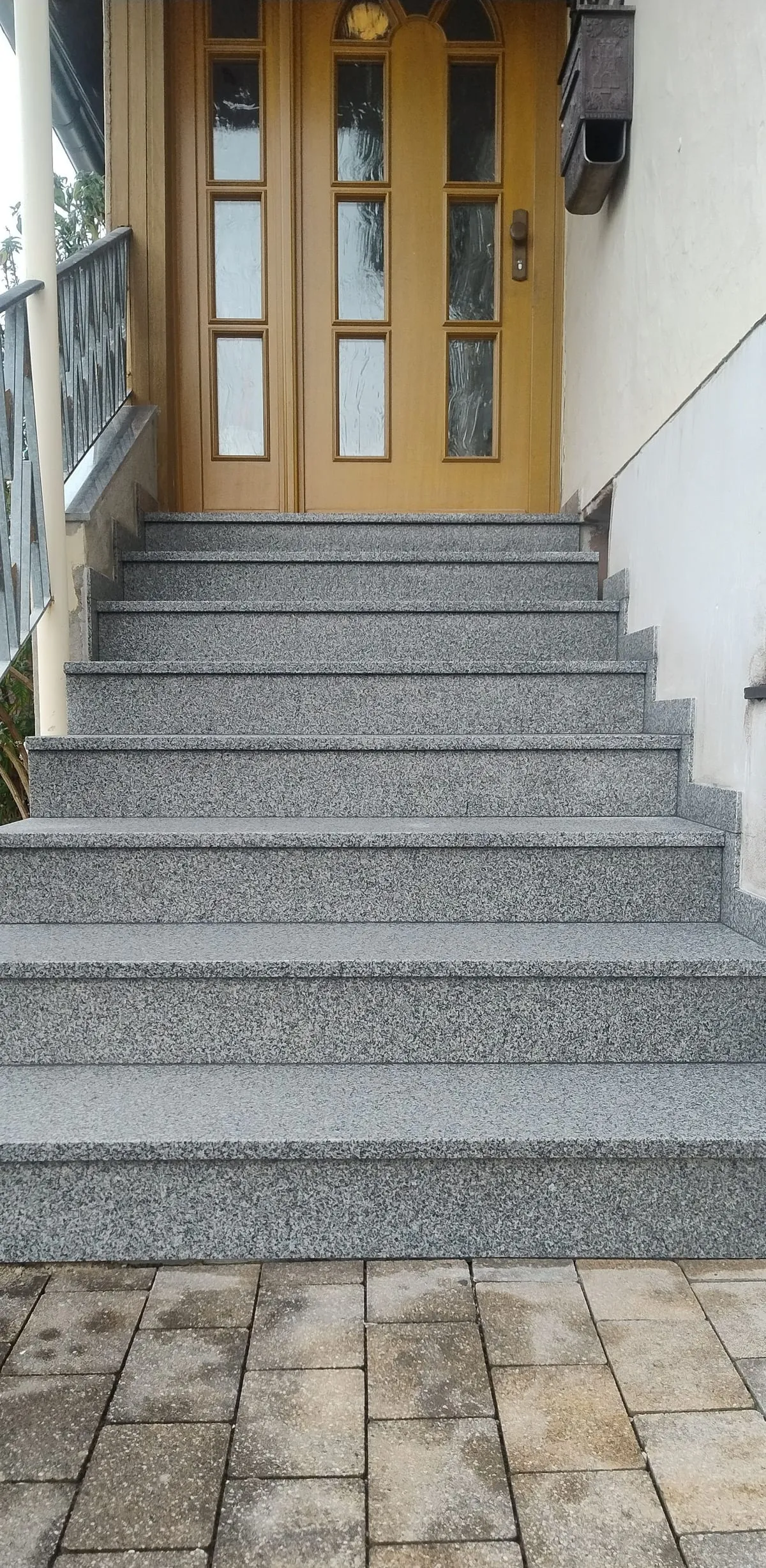 Die sanierte Treppe: neue Stufen aus grauem Granit führen zur gelben Haustür hinauf