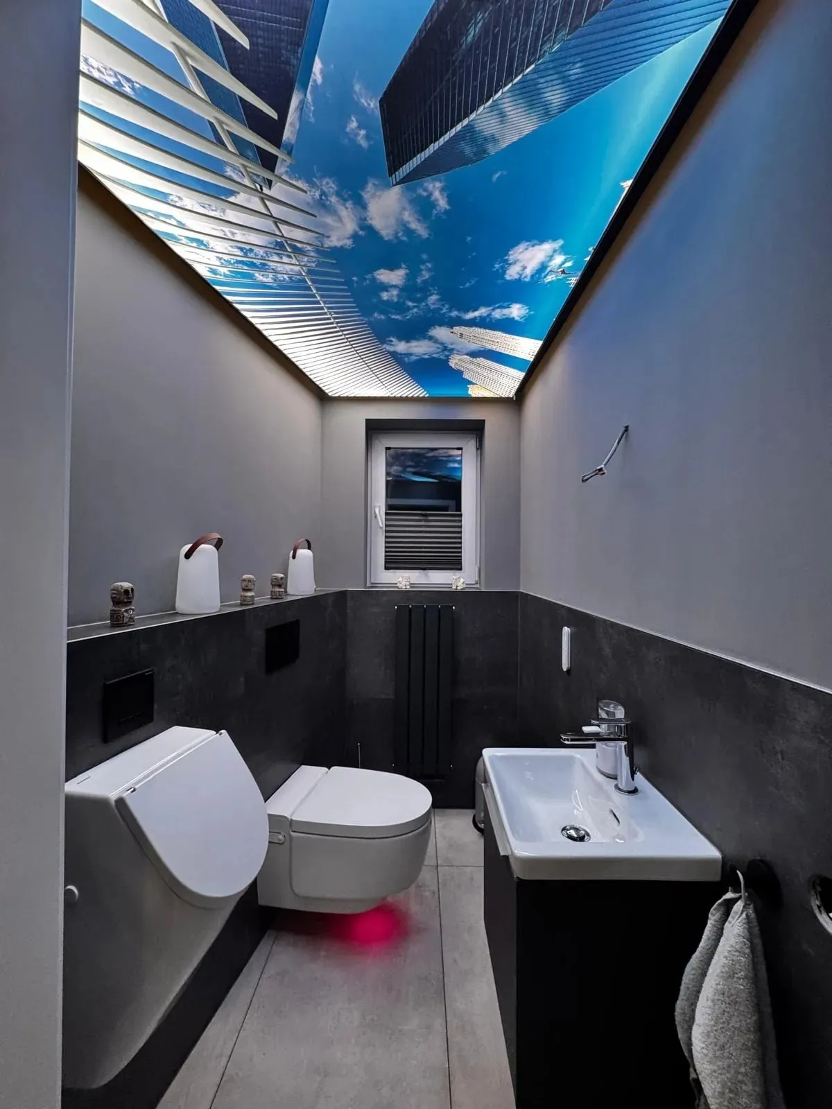 Blick zur beleuchteten Lichtdecke mit Himmelmotiv über dem neu gefliesten Gäste-WC